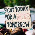 In the crowd of a protest a banner reads "Fight for a better tomorrow".